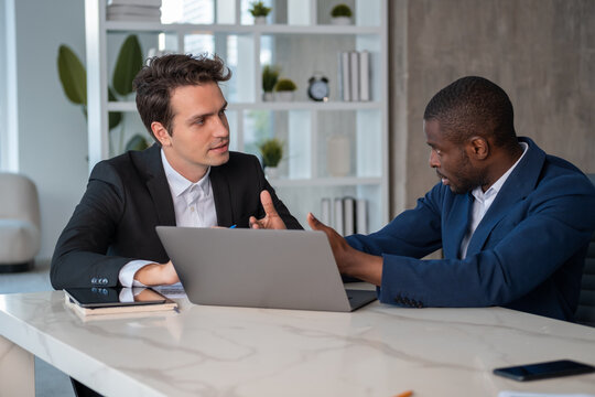 Attentive African American businessman talking to colleague explaining project