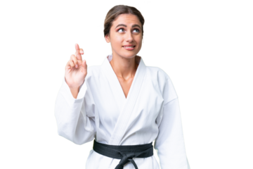 Young Uruguayan woman doing karate over isolated background with fingers crossing and wishing the best