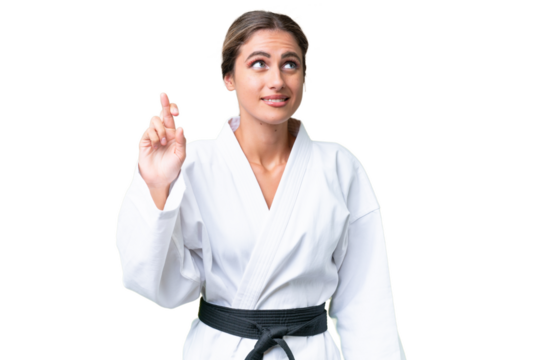 Young Uruguayan woman doing karate over isolated background with fingers crossing and wishing the best