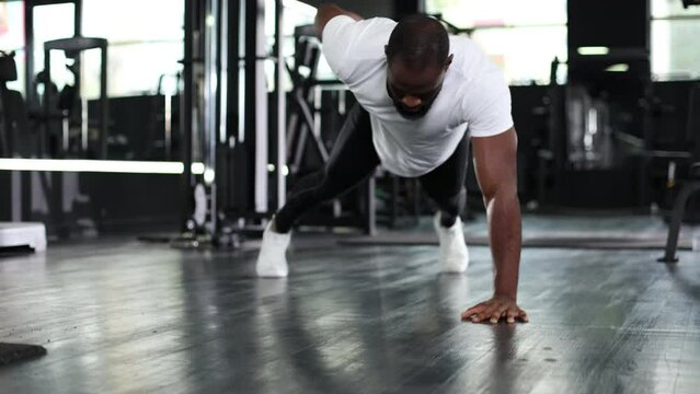 Sporty african man doing push-up in a gym.