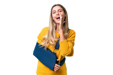 Young Uruguayan woman with broken arm and wearing a sling over isolated background shouting with...