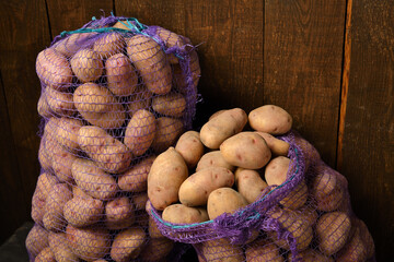 two bags of potatoes on a dark wooden background