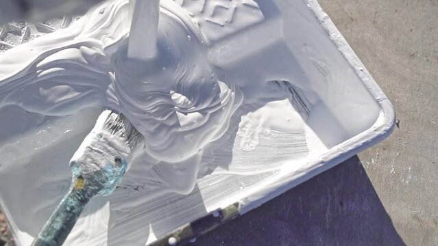 White construction paint is poured into a paint tray. Outdoors. Slow motion