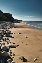 Vertical shot of a sandy beach with rocks and a cliff in Compton bay, Isle of Wight