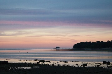 Purple and orange sky over a beach and a cliff with a bridge in Bembridge, Isle of Wight