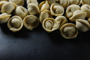 Close-up of many handmade dumplings on a black background.
