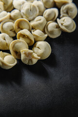 Close-up of many handmade dumplings on a black background.