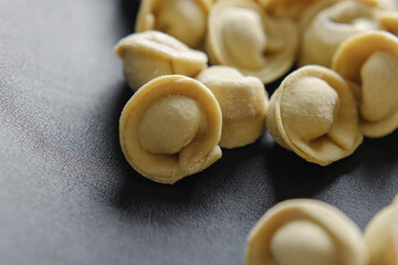 Close-up of many handmade dumplings on a black background.