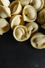 Close-up of many handmade dumplings on a black background.