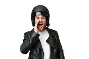 Young caucasian man with a motorcycle helmet isolated on green chroma background shouting with mouth wide open