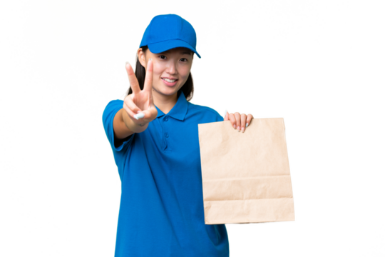 Young Asian woman taking a bag of takeaway food over isolated background smiling and showing victory sign