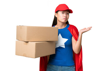 Super Hero delivery Asian woman holding boxes over isolated background having doubts while raising...