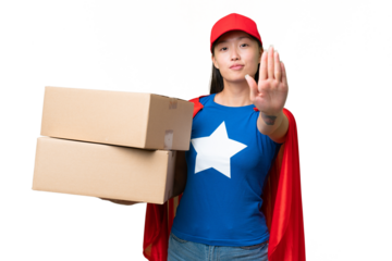 Super Hero delivery Asian woman holding boxes over isolated background making stop gesture