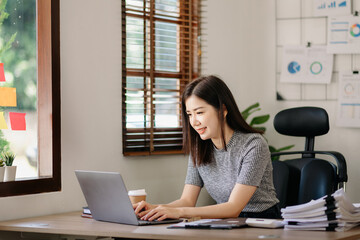  Beautiful Asian business woman typing laptop and tablet Placed at the table at the office