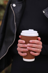cup with coffee in female hands, street photo, fast food concept. Vertical Orientation