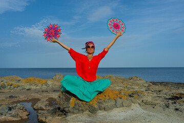 A woman holds in her hands a mandala made of multi-colored threads. Boho style clothes. On the...