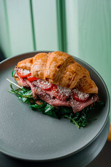 very testy croissant sandwiches with meat, tomato and salad on the plate