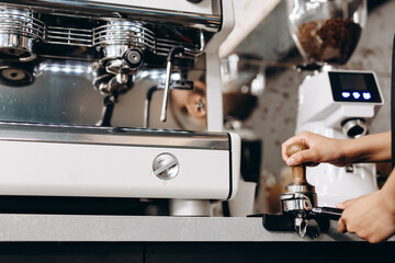Close-up of hand Barista cafe making coffee with manual presses ground coffee using tamper at the coffee shop.