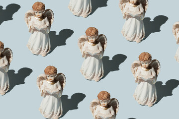 statues of angels praying on a blue background. Christmas pattern