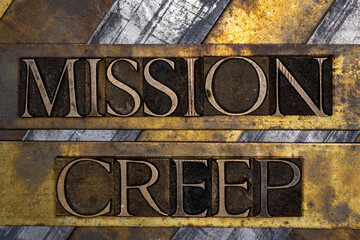 Mission Creep with barbed wire on grunge textured copper and gold background
