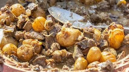 Traditional Asian dish kaurdak of fried meat, liver, kidneys, liver, potatoes, onions on a wooden platter. Close-up