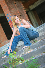 Young woman in rough clothes posing in an abandoned house
