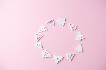 small white Christmas tree figurines laid out in the shape of a Christmas ball on a pink background with a place for text , Christmas concept, gifts,sale