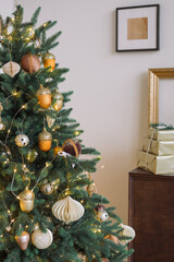 Christmas Tree decorated in gold colors and wrapped gift boxes at home. Winter holidays background.