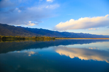 Lake in the mountains. Beautiful nature, reflection of clouds and mountains in blue water. Kyrgyzstan, Lake Issyk-Kul