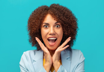 Happy young African American woman with curly hair screaming wow on blue background. Good news, sale, shopping or big discounts concept