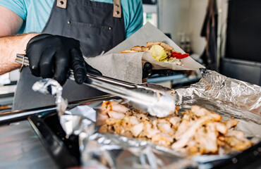 process of preparing traditional greek fast food - gyros. chef hand cooking food on food truck kitchen