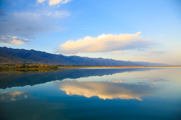 Naklejka na ściany i meble Lake in the mountains. Beautiful nature, reflection of clouds and mountains in blue water. Kyrgyzstan, Lake Issyk-Kul