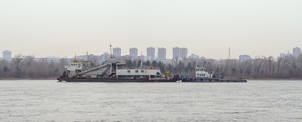 Hopper dredger and tugboat on the river.