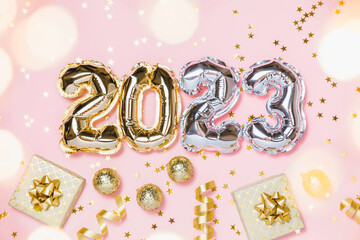 New year 2023 balloon celebration card. Gold and silver foil balloon number 2023, party decoration, gold confetti on pink background. Flat lay, merry christmas, happy holidays concept.
