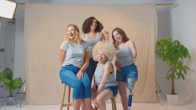 Group of casually dressed diverse smiling women friends, one with prosthetic leg, in studio promoting body positivity - shot in slow motion