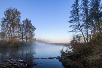 Naklejka na ściany i meble River bank in the morning in the fall with fog. 