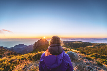 Sitting woman watching the sunrise over the beautiful mountain landscape of Pico do Ariero. Pico do...
