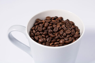 close up of a mug filled with coffee beans on a white background