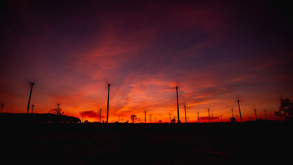 Aerial view of powerful wind turbine farm for pure energy production on beautiful sunset sun setting behind wind turbine producing alternative energy for sustainable development. renewable energy