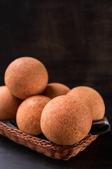 Beautiful shot of round Colombian tradition food bunuelo on wooden plate isolated on dark background