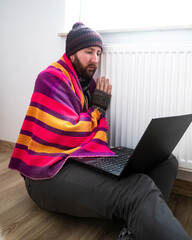 man freezes while working in office; cold at home; cold at work; energy crisis 2022; winter 2022; blackout; no heating; energy problems in europe; home office; gas crisis