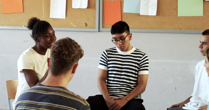 Group of multi-ethnic students sitting in a circle in a classroom while talking about their emotions. Emotional education, assembly, high school 