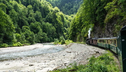 Vintage steam train chugging through the Carpathians Mountains in Maramures Romania.