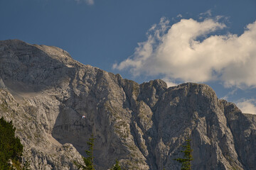 Paragleiter fliegt vor einer massiven Felswand