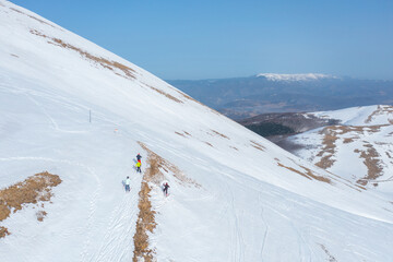 A group of skiers away from the track on a very steep part of a snow-covered mountain in winter