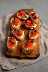 Homemade Lox And Cream Cheese Crostini on a wooden board, side view.