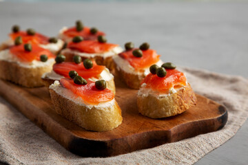 Homemade Lox And Cream Cheese Crostini on a wooden board, side view. Close-up.