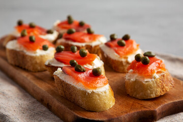 Homemade Lox And Cream Cheese Crostini on a wooden board, side view. Close-up.