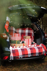 Car trunk full of gift boxes, presents and garland for Christmas holidays. forest outdoor