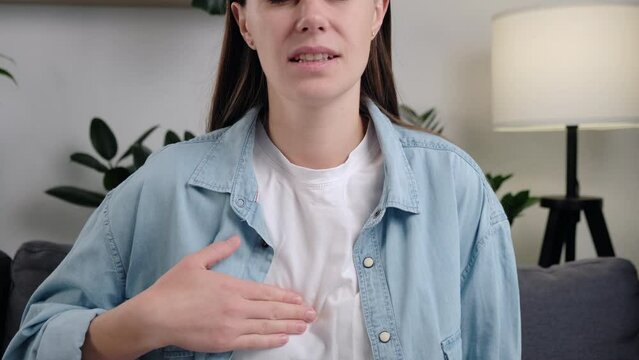Cropped shot of upset unhealthy young caucasian woman sitting on couch at home having reflux acids and pain in chest. Gastroesophageal Reflux Disease have frequent belching. Healthcare medical concept